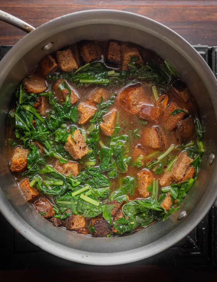 A top-down image of pane cotto cooking in a small pot before the bread's absorbed the liquid.