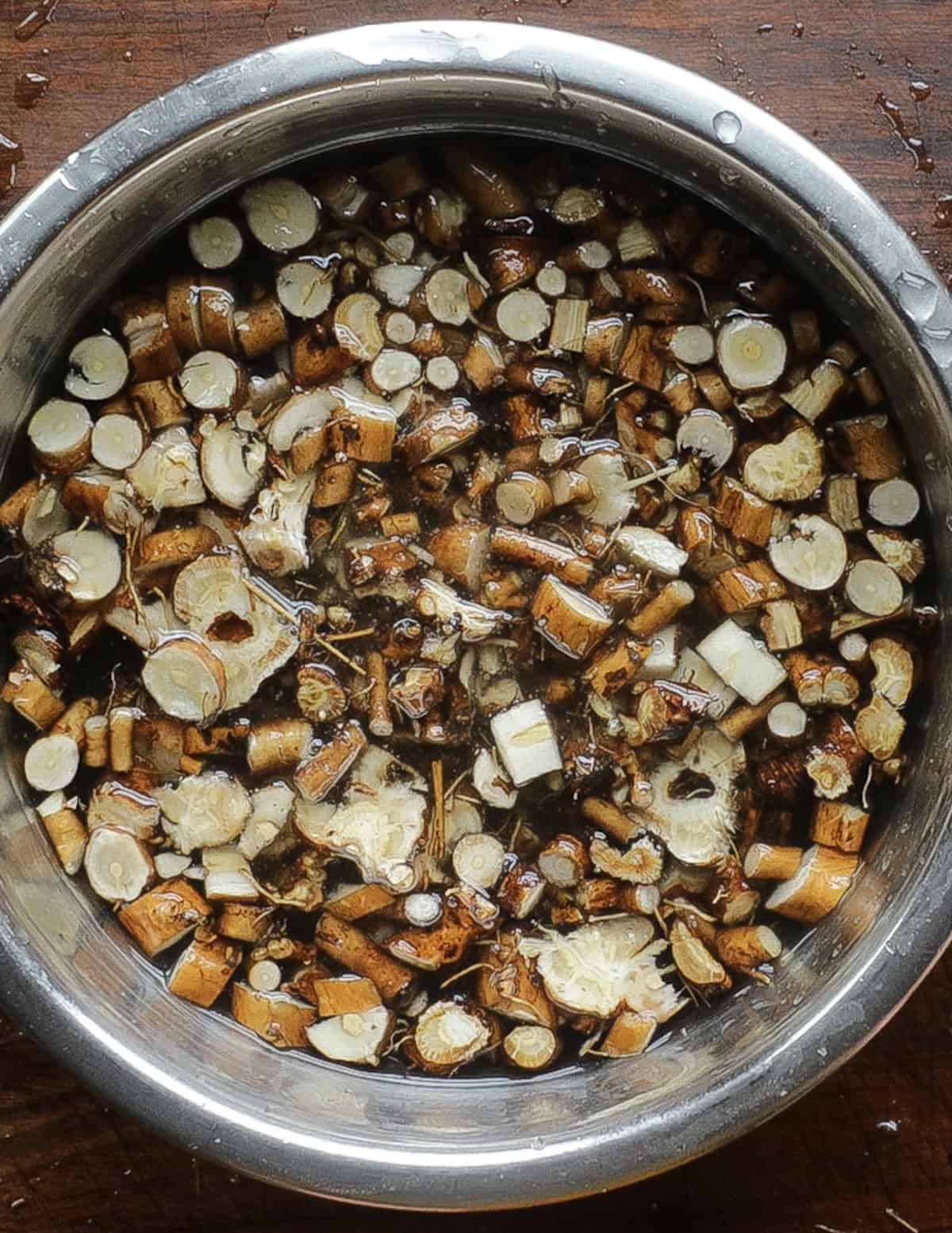 Washing cut dandelion roots in water a second time to ensure they're free of dirt.