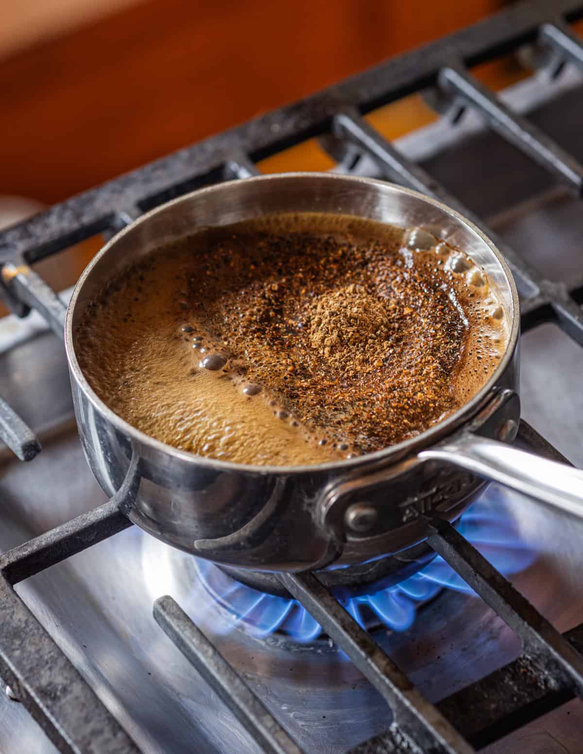 Boiling ground dandelion roots in water to make dandelion or chicory coffee.