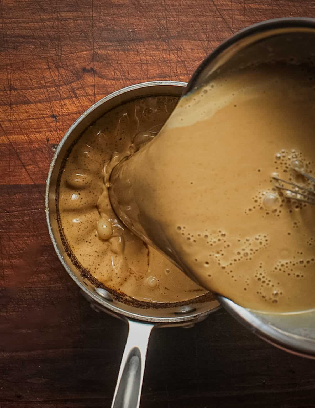 Pouring dandelion ice cream base back into a pot to cook until thickened.