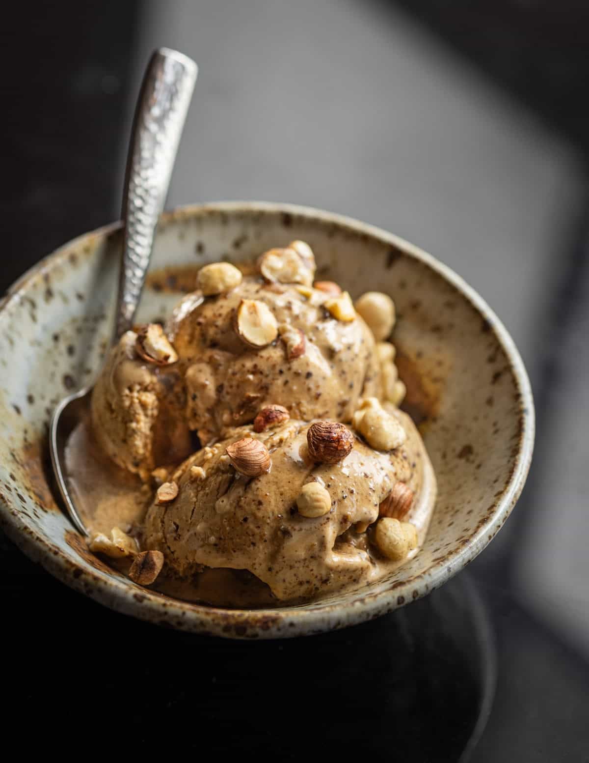 Dandelion ice cream made from roots in a bowl garnished with wild hazelnuts and black walnuts.