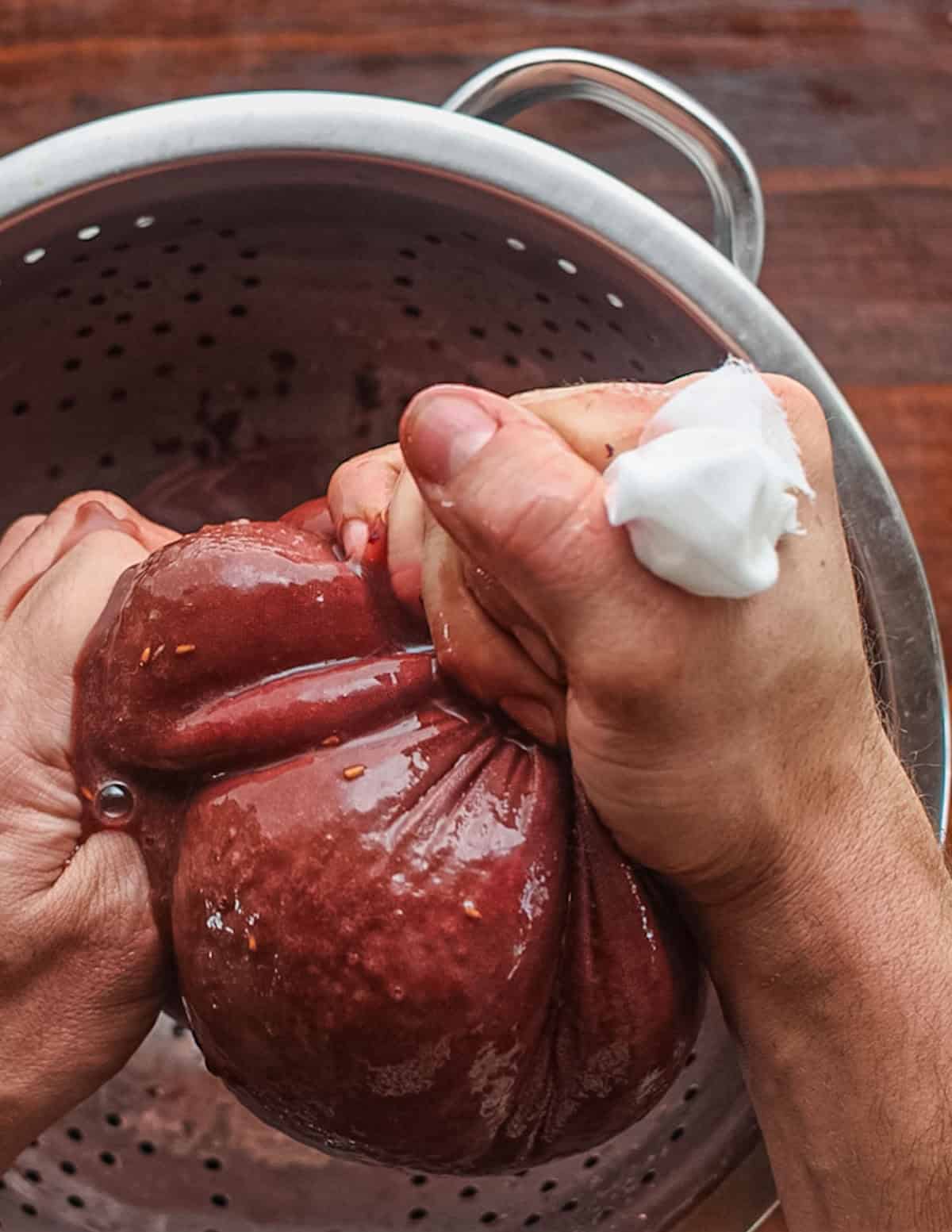 Squeezing cheesecloth to extract elderberry juice.