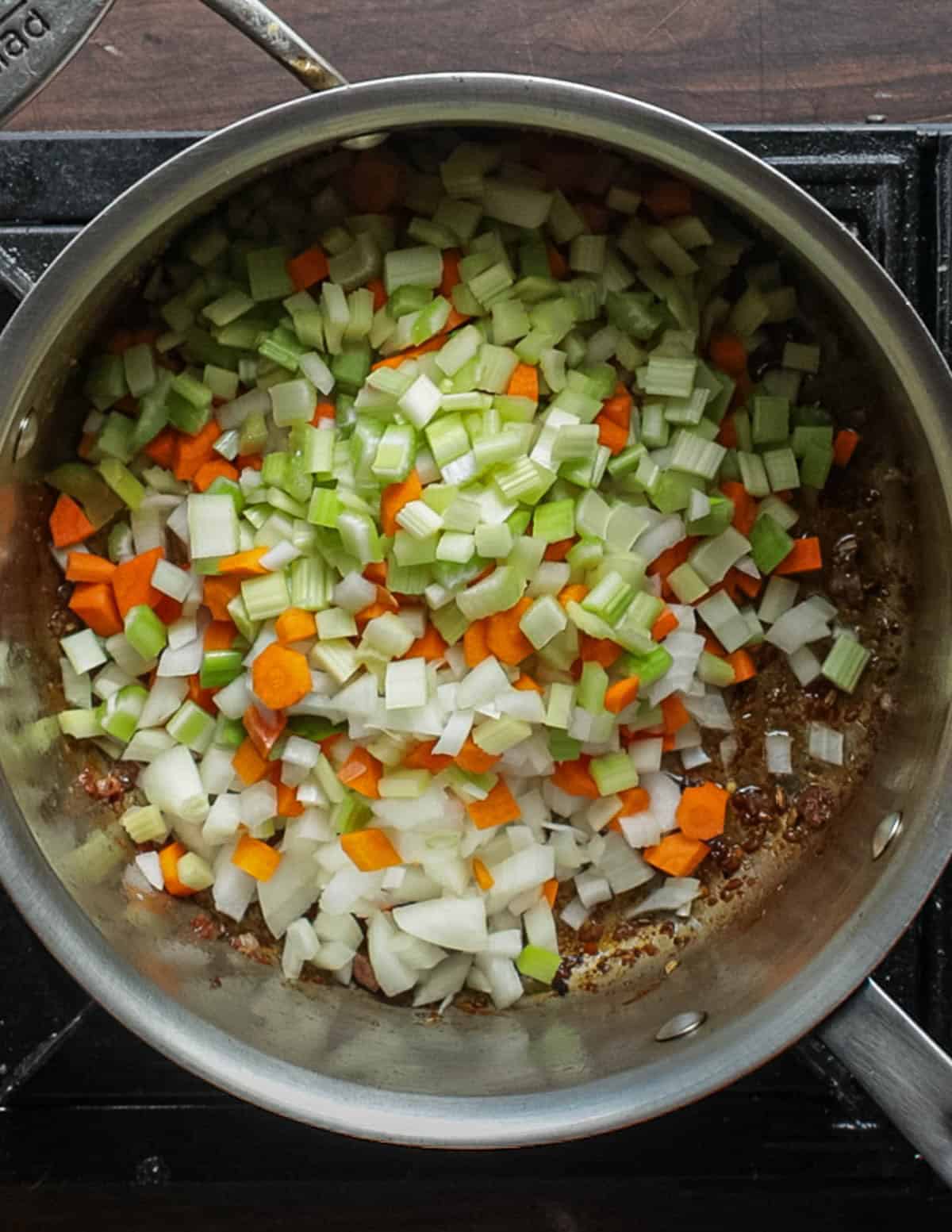 Slowly cooking carrot, onion and celery in a pot for soup.