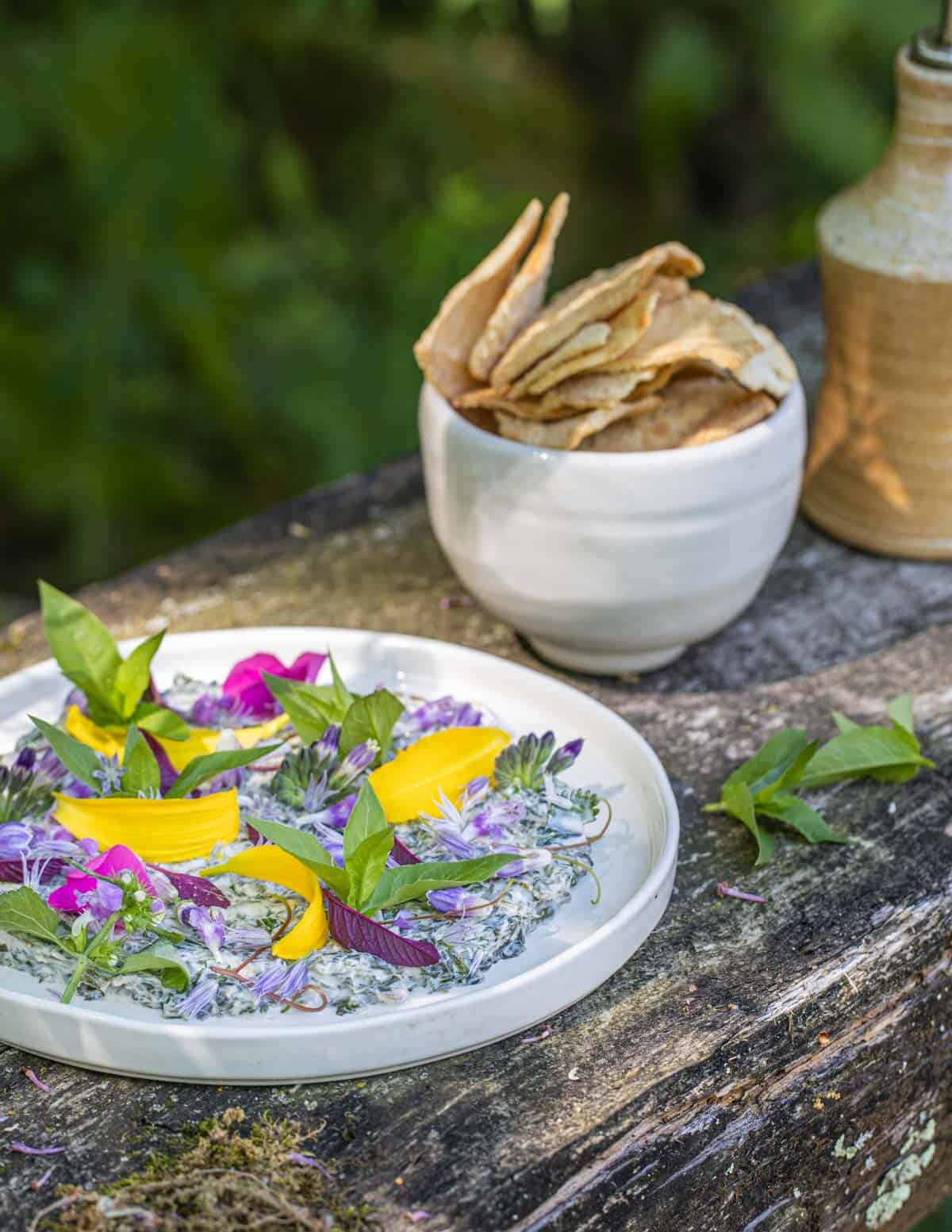 A dip made from mallow greens, herbs, spices and yogurt garnished with wild flowers and toasted pita chips