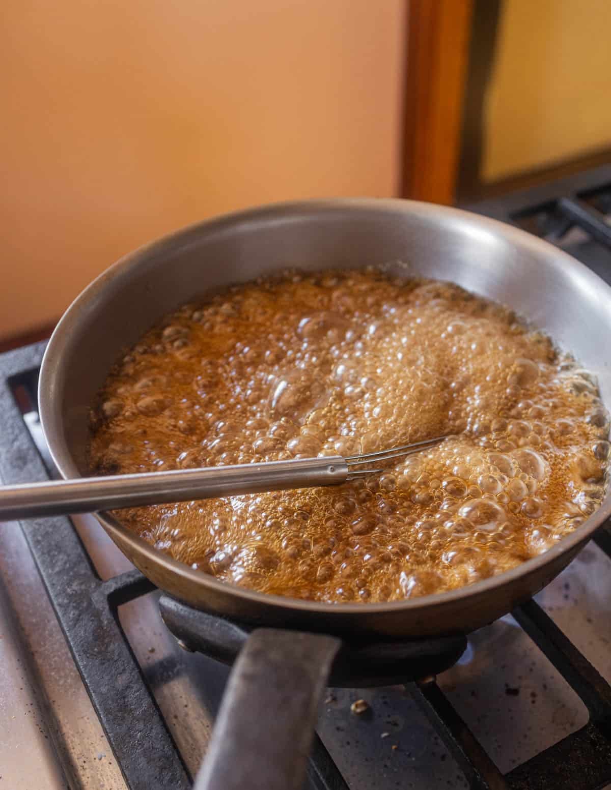 Boiling maple syrup, brown sugar, cream and butter in a pot.