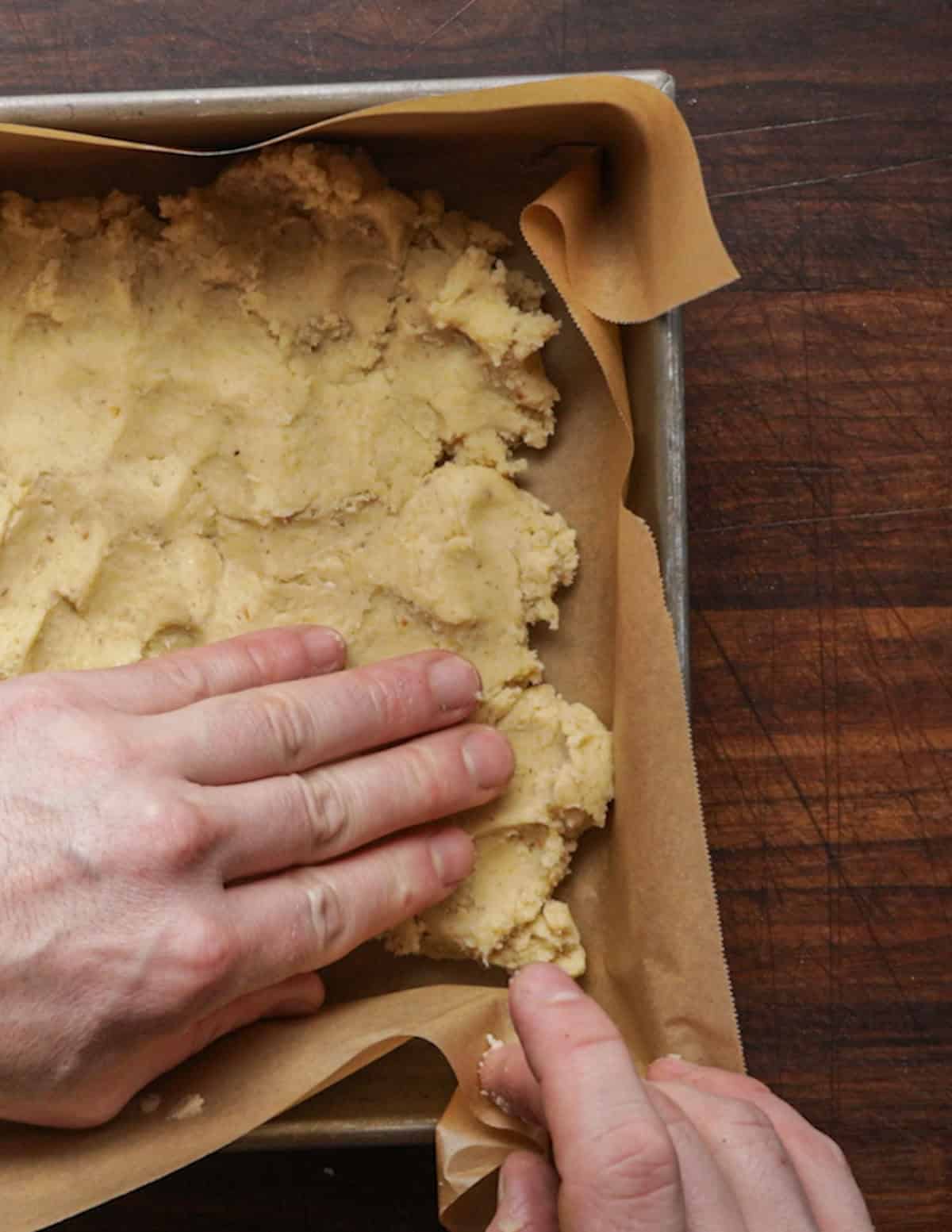 Pressing bar cookie dough into a baking pan.