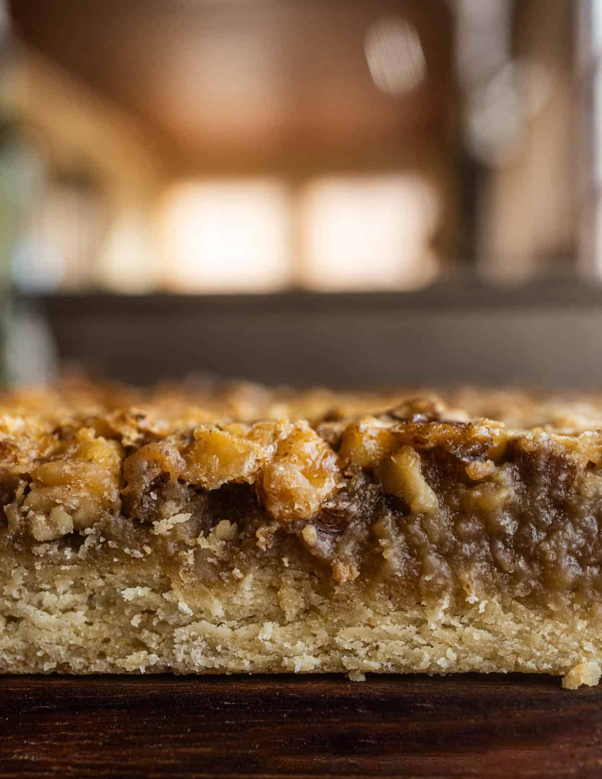 A close up image of maple walnut bar cookies showing the layers of crust, filling and nuts.