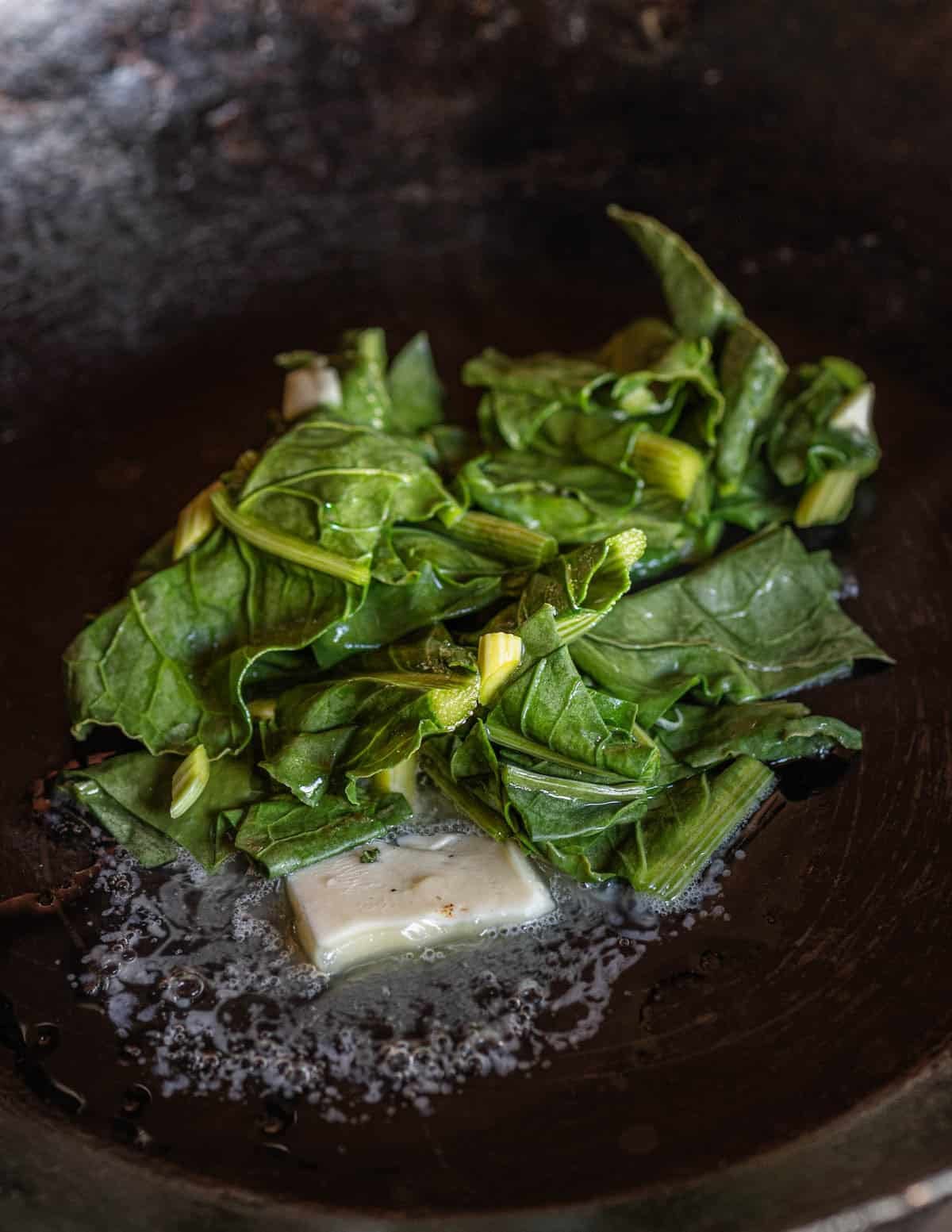 Cooking dock leaves in a pan with butter.
