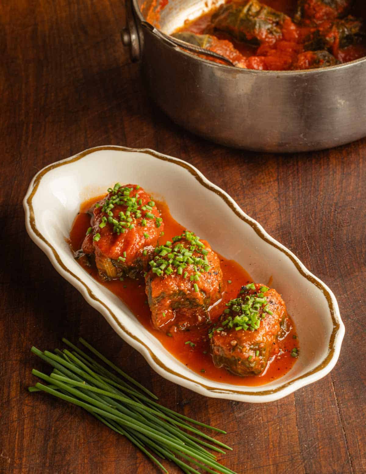 Sausage stuffed dock leaves in tomato sauce.