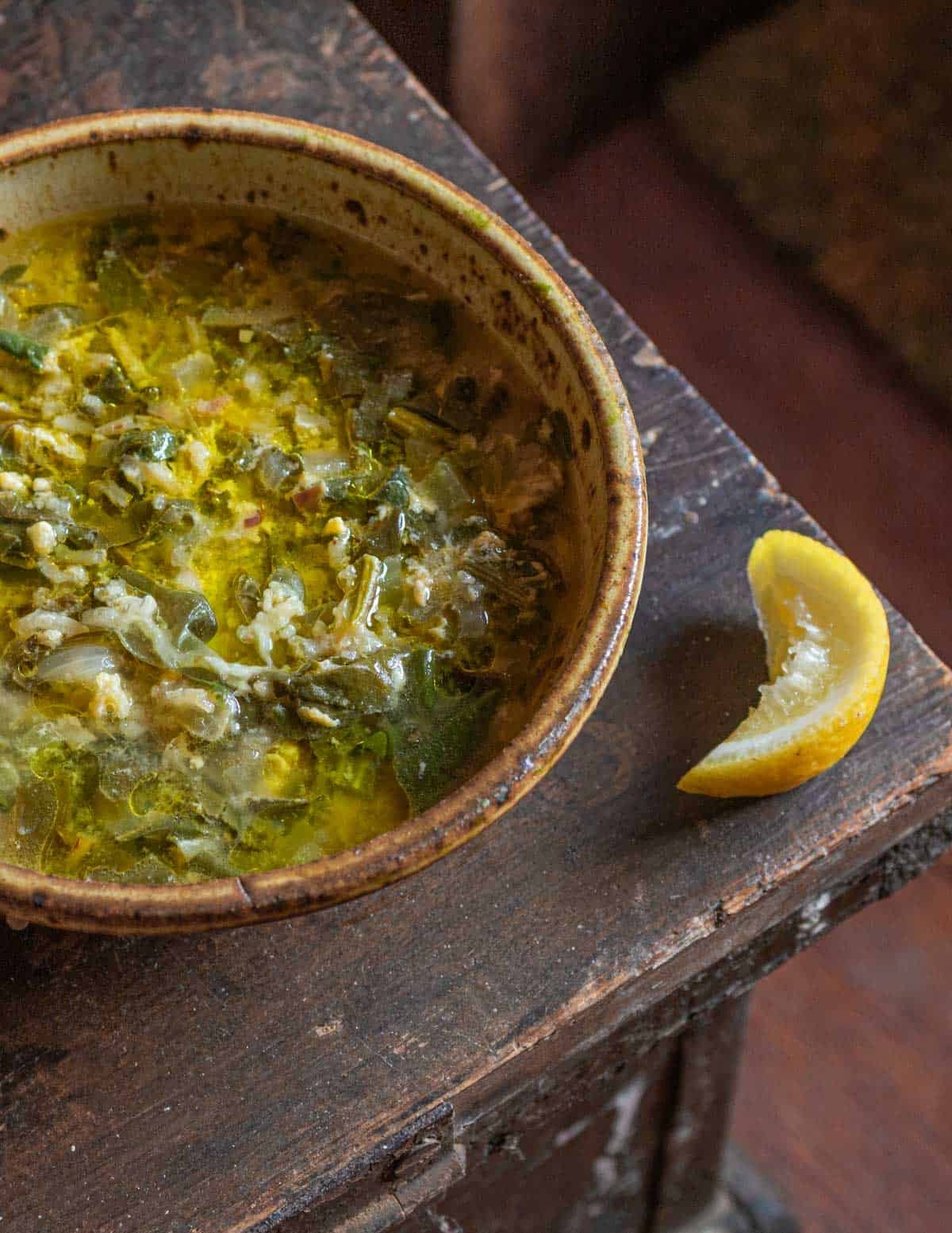 A bowl of curly dock soup with rice, egg and lemon.