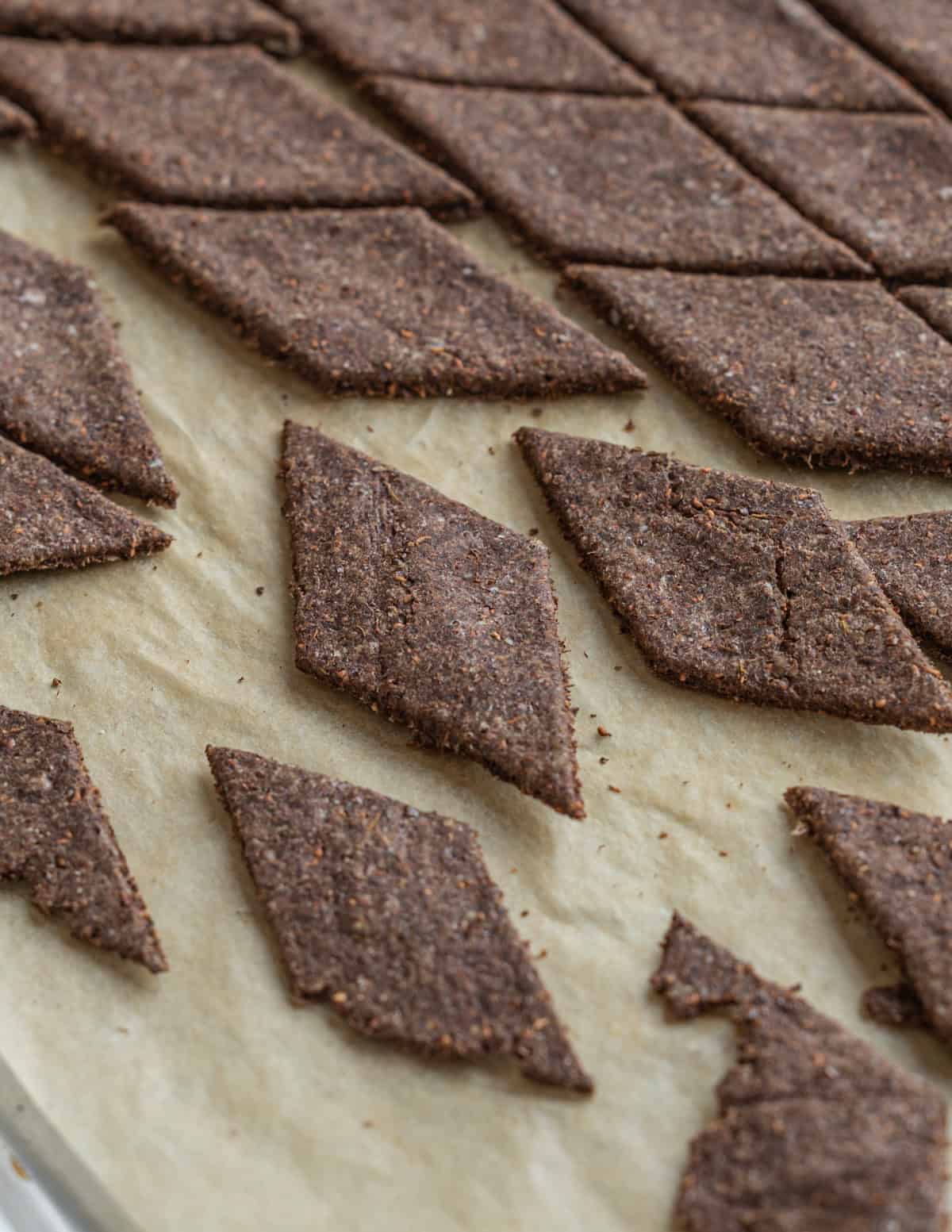 Dock seed crackers on a baking sheet being cut after baking.
