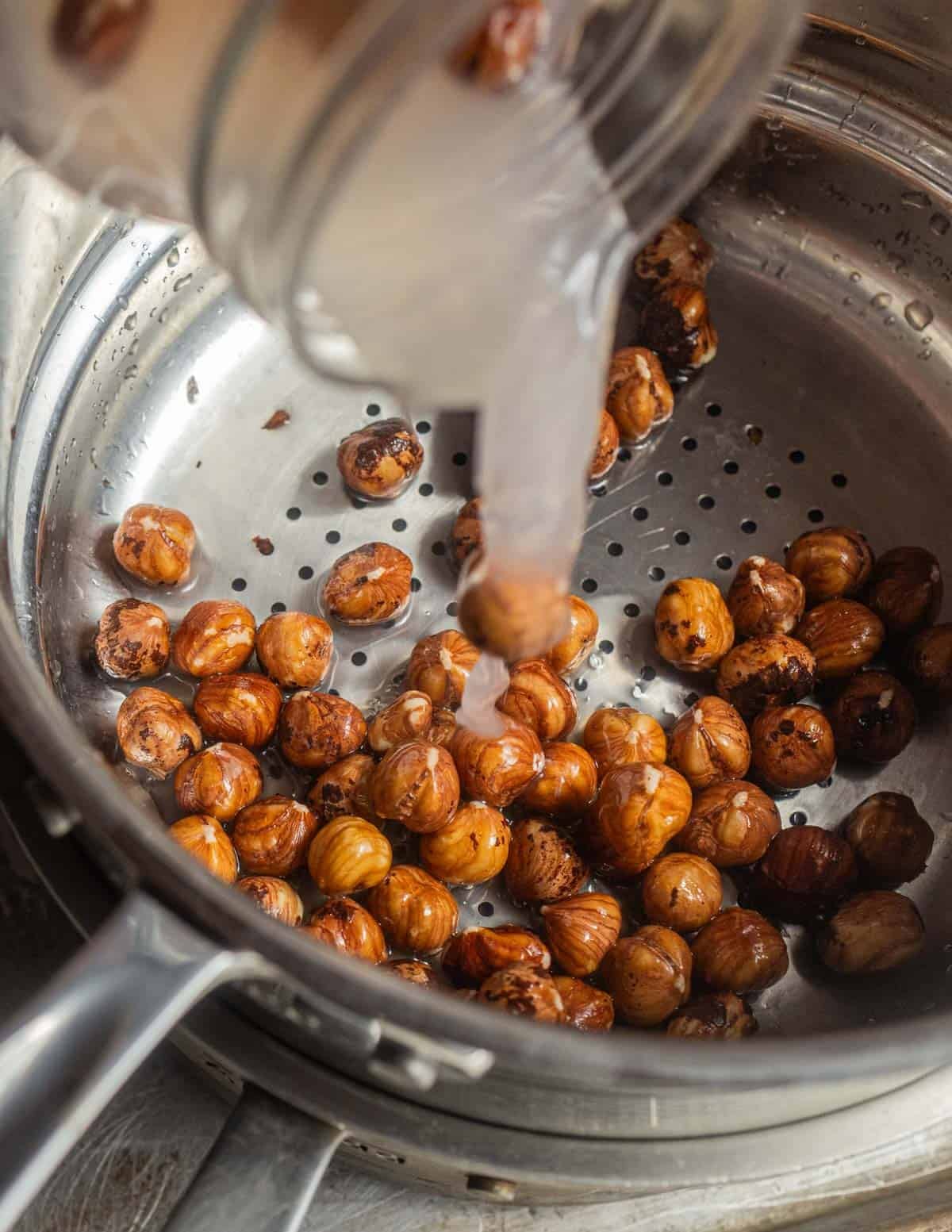 Straining soaked hazelnuts into a colander.