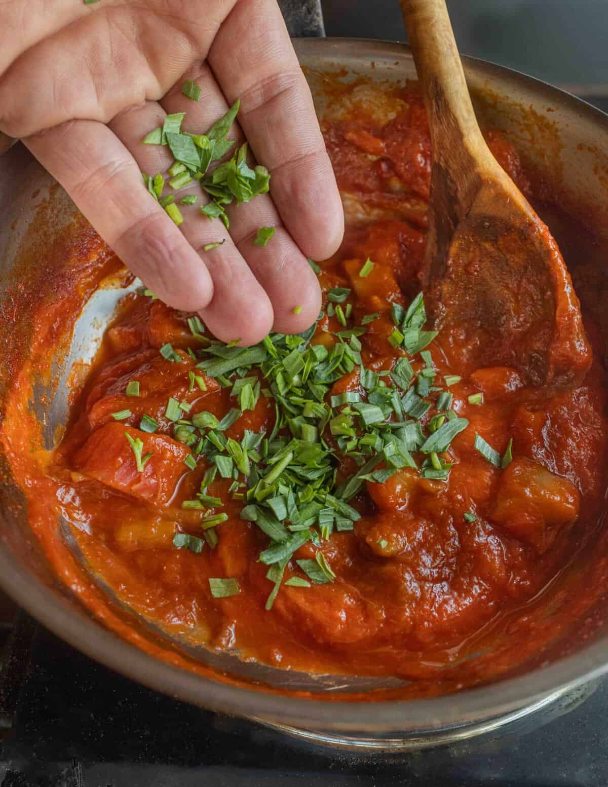 Adding a handful of chopped fresh herbs to a pan of rhubarb sauce.