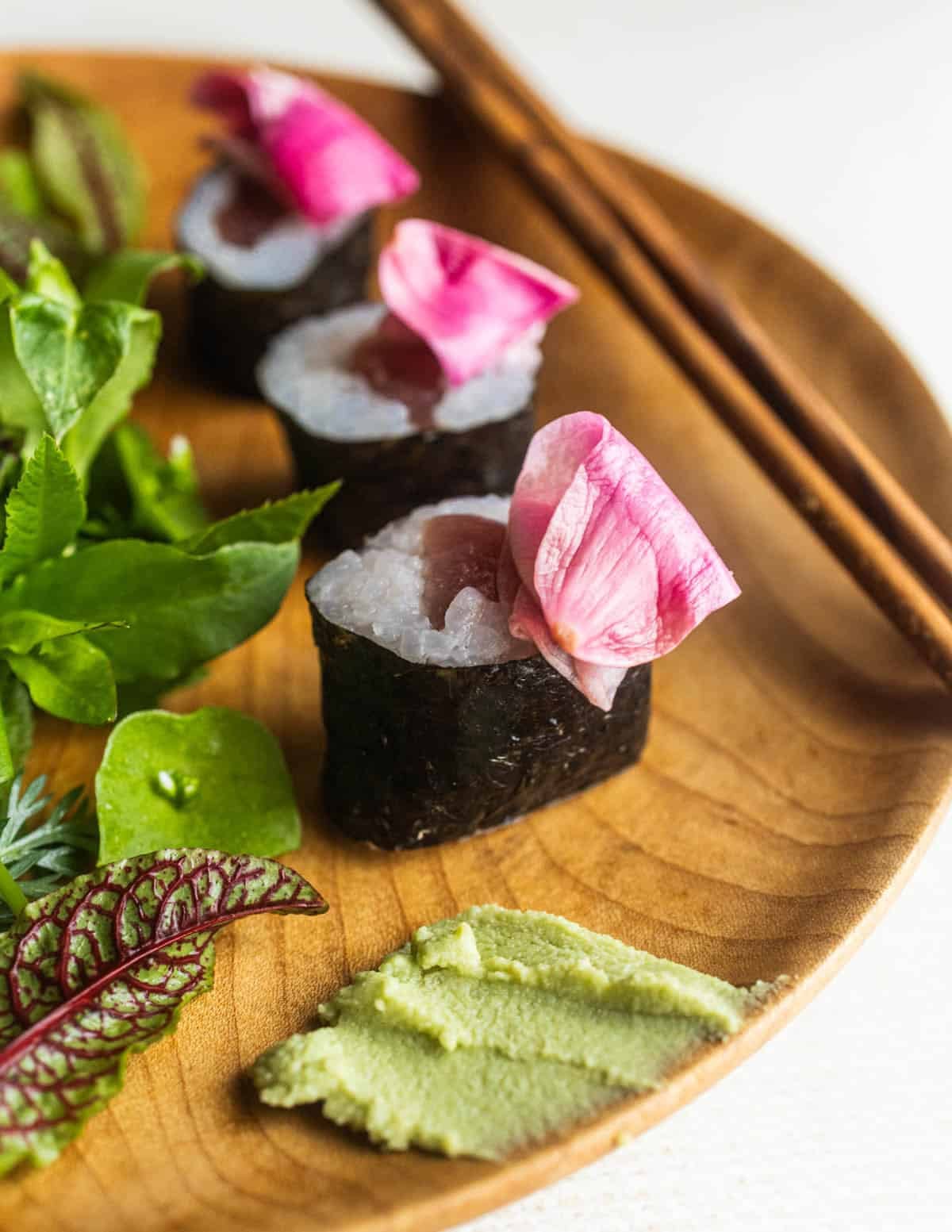 A plate of sushi garnished with pickled magnolia flowers. 