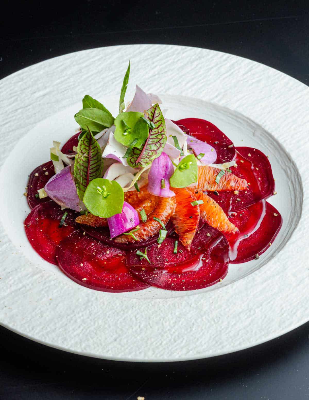 A salad of shaved roasted beets with blood orange, magnolia petals and miners lettuce. 