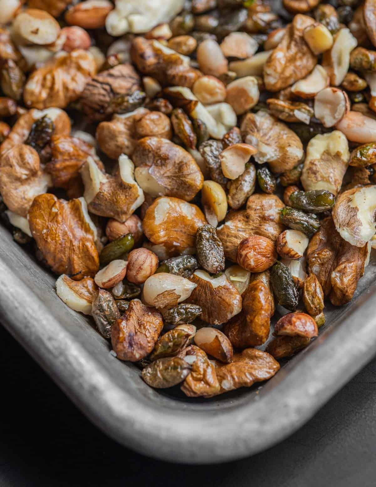 A small baking sheet with wild pine nuts, wild hazelnuts, black walnuts, and maple seeds ready to cook.