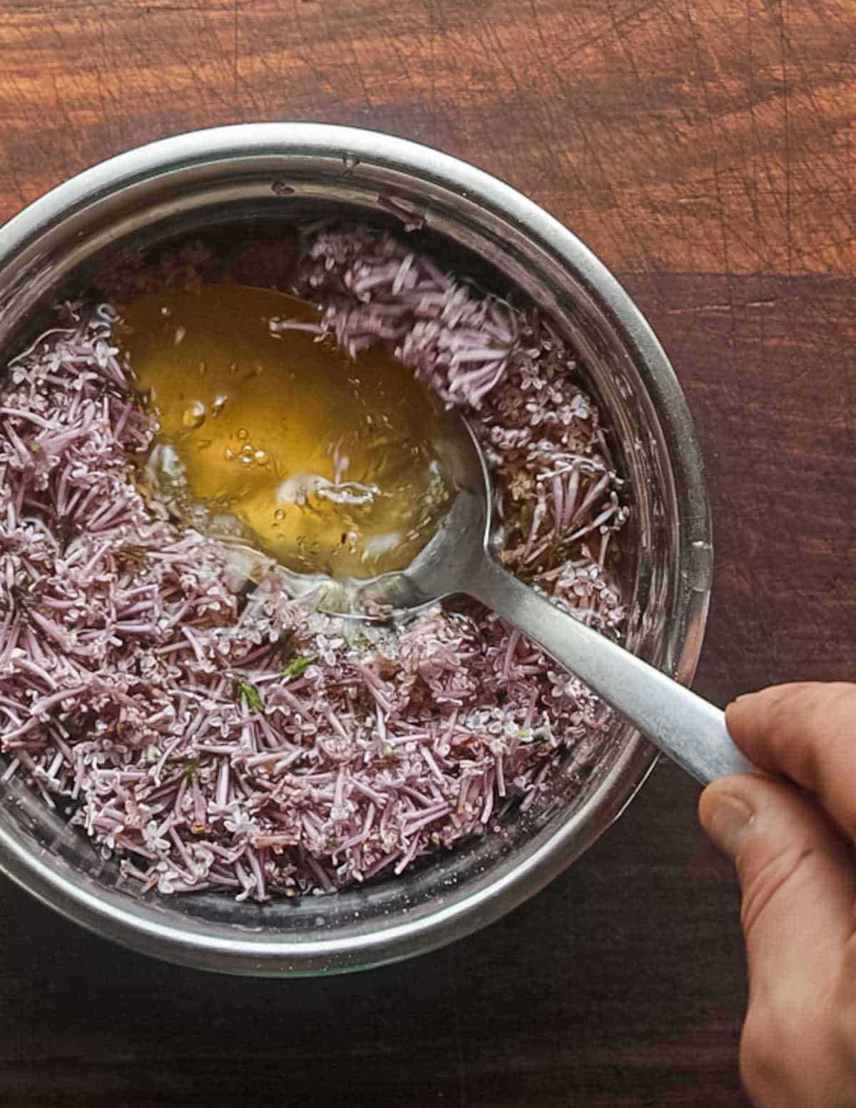 Pressing lilac flowers underneath syrup to infuse.