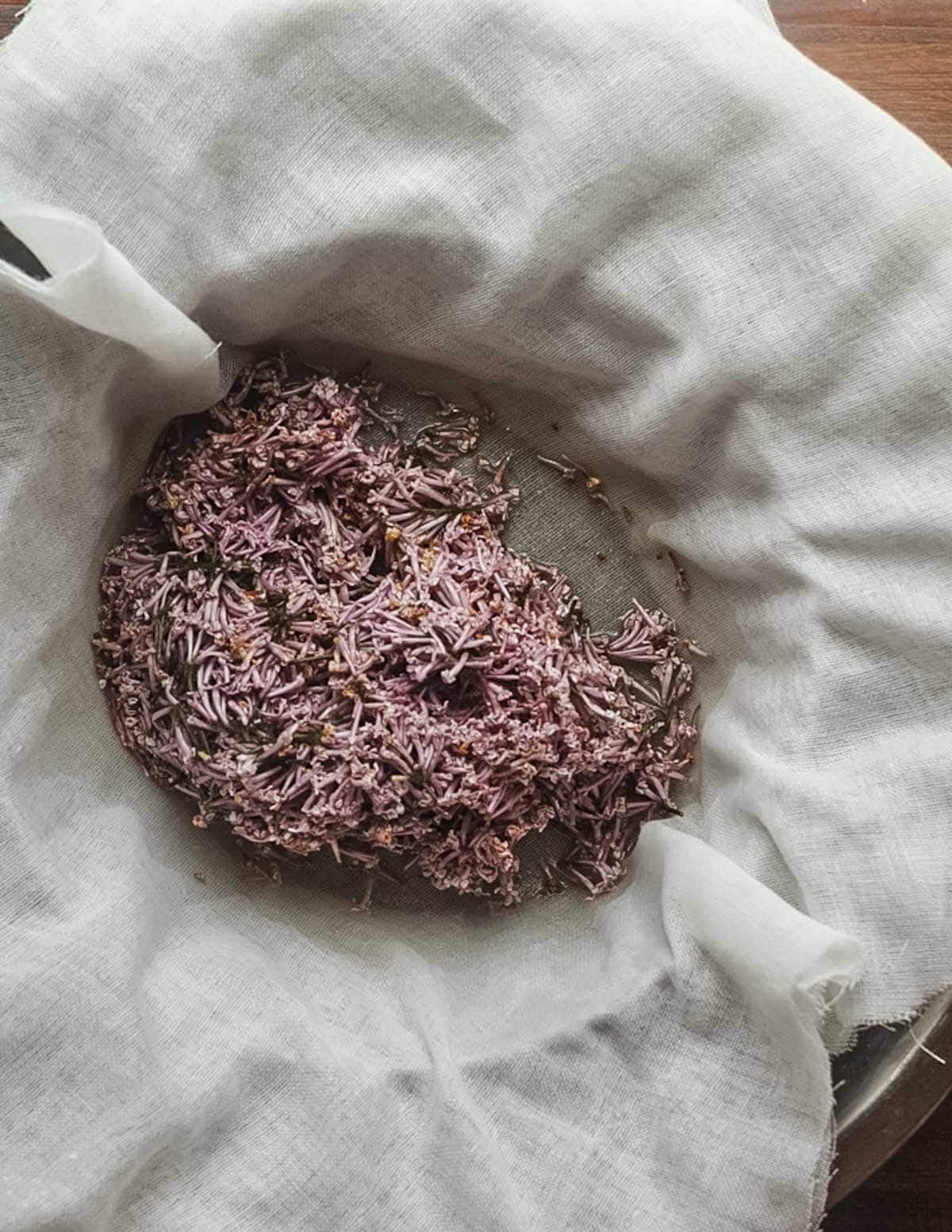 Straining lilac syrup through cheesecloth.