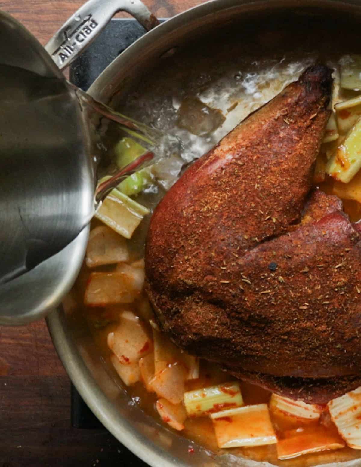 Adding water to a pot with a smoked wild turkey leg.