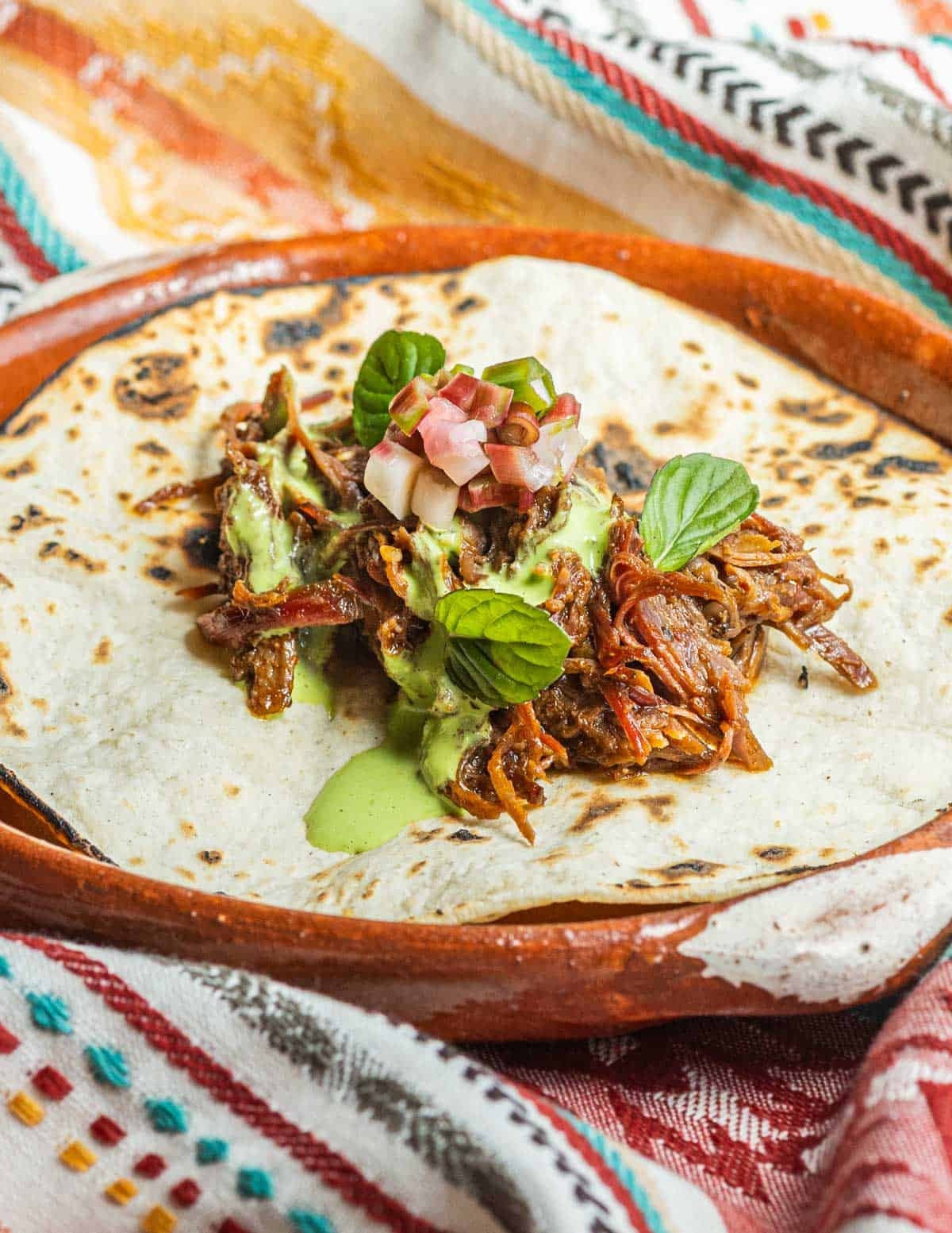 Wild turkey tacos on a corn tortilla with pickled ramps, sour cream, and wild mint.