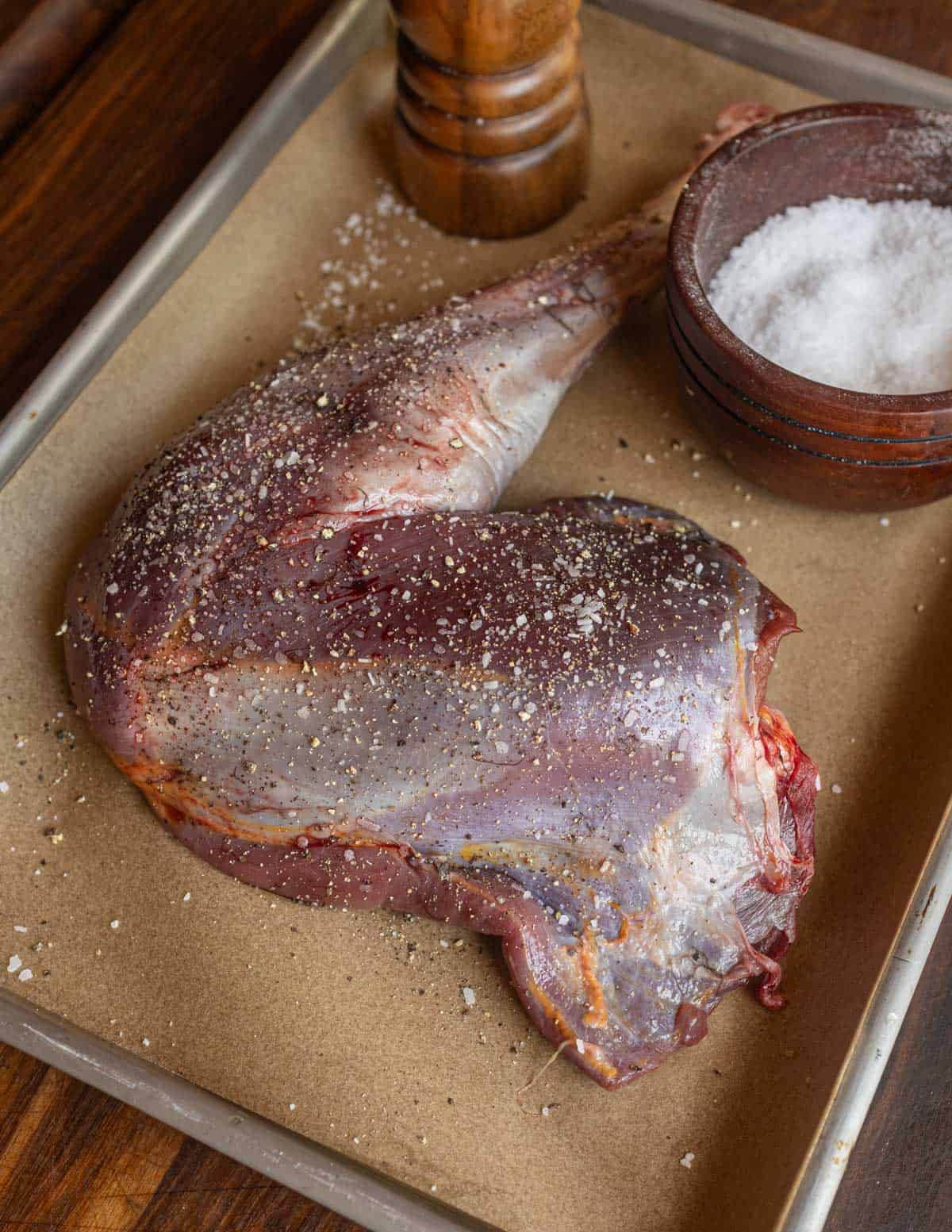 Seasoning a wild turkey leg with salt and pepper.