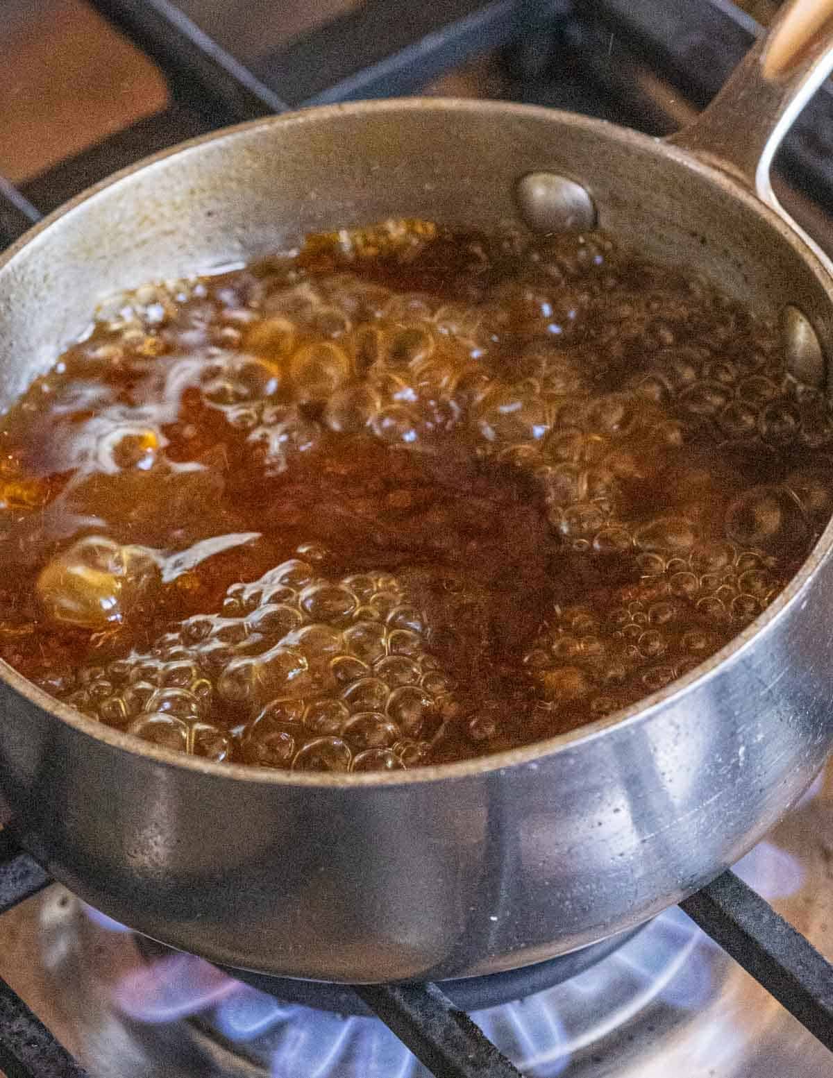A close up image of reducing and boiling the cooking liquid from a leg of wild turkey on the stove.