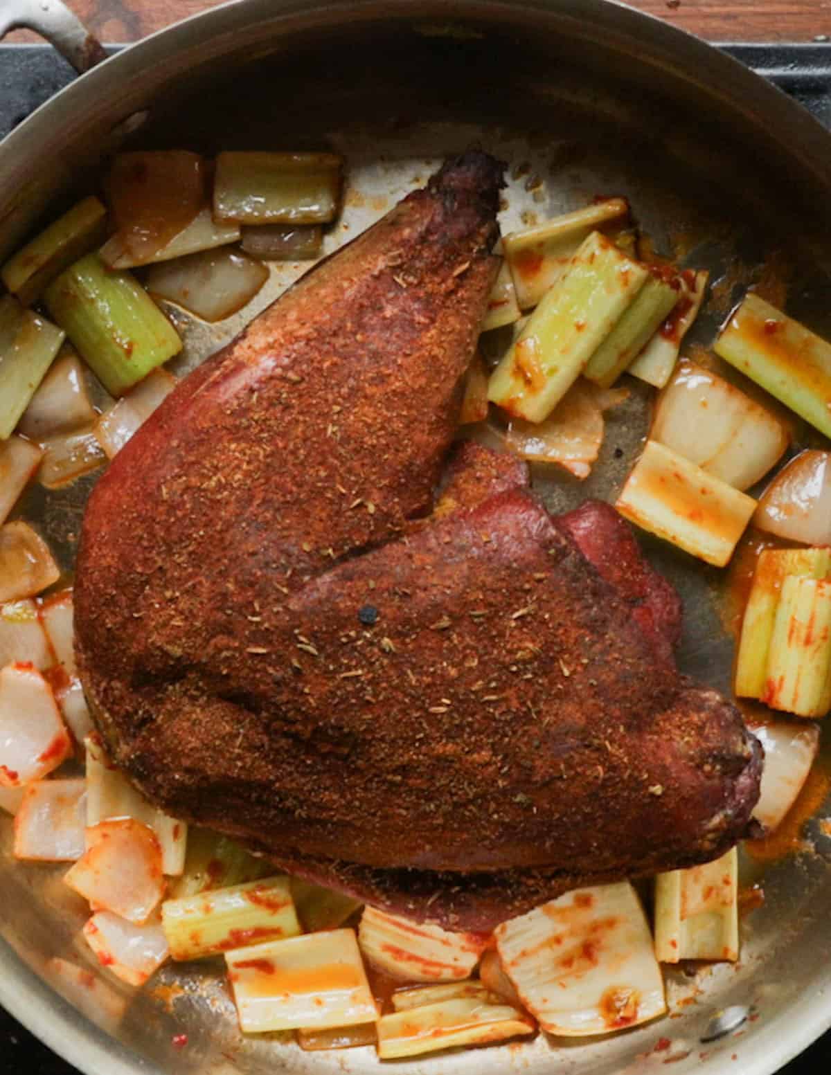 Putting a smoked wild turkey leg in a pot with celery, onions and tomato paste.