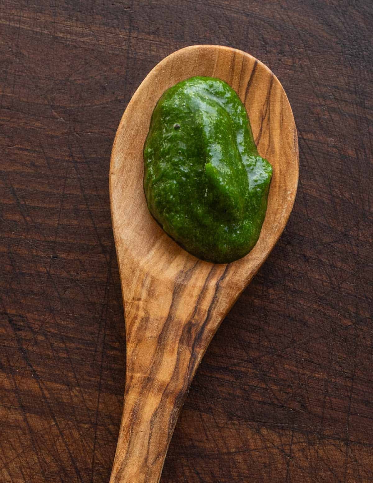 A spoonful of dark green pureed ramp leaves on a spoon.