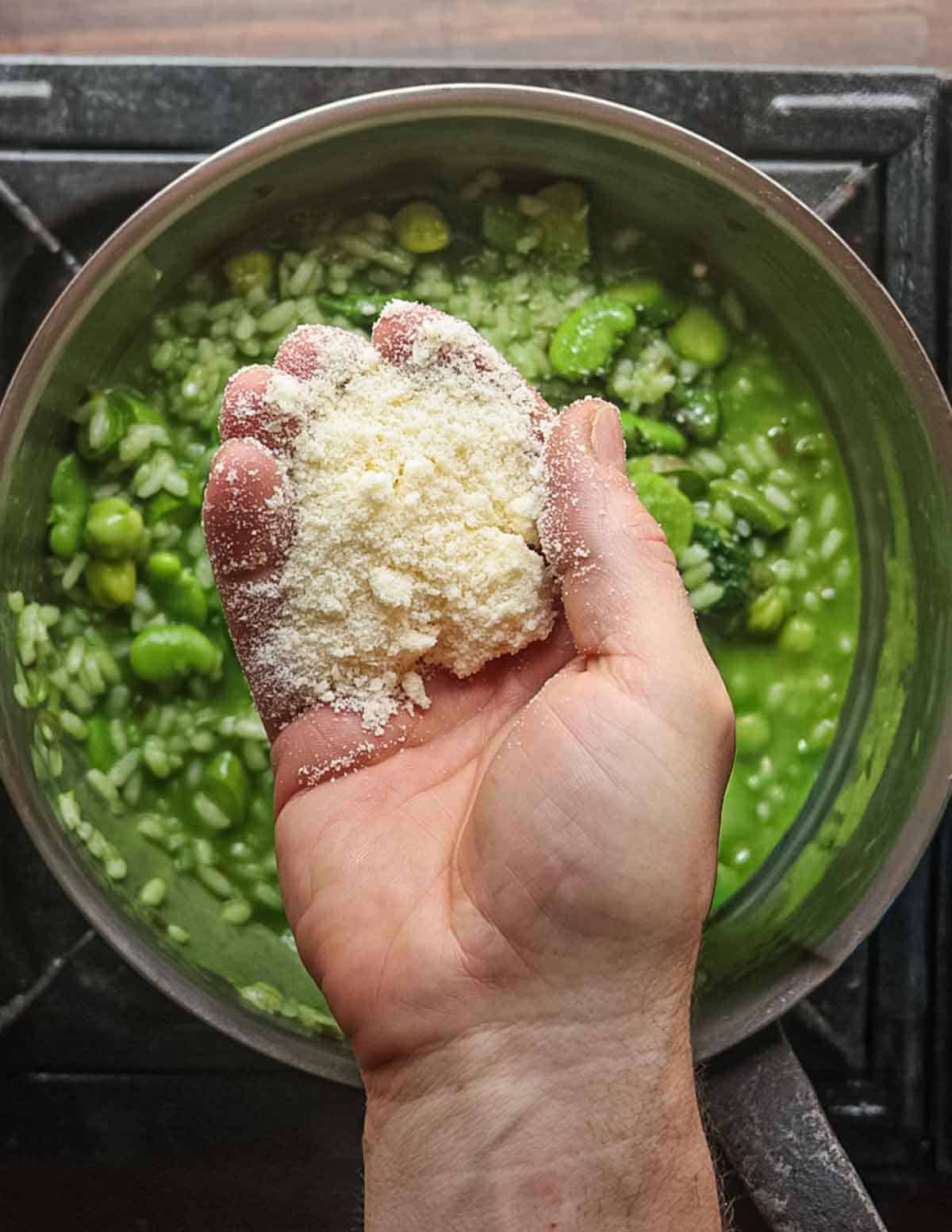 Adding a handful of cheese to a green risotto.