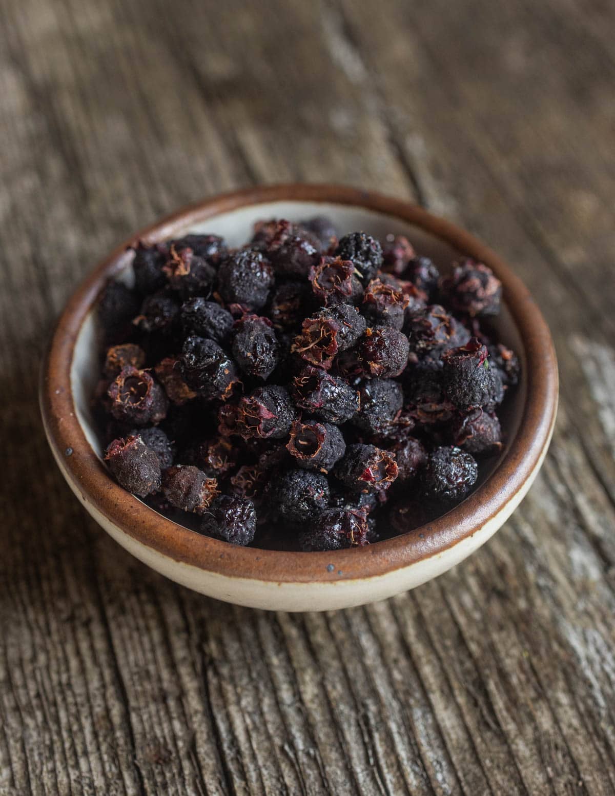 A small bowl of dried serviceberries in a white ramekin.