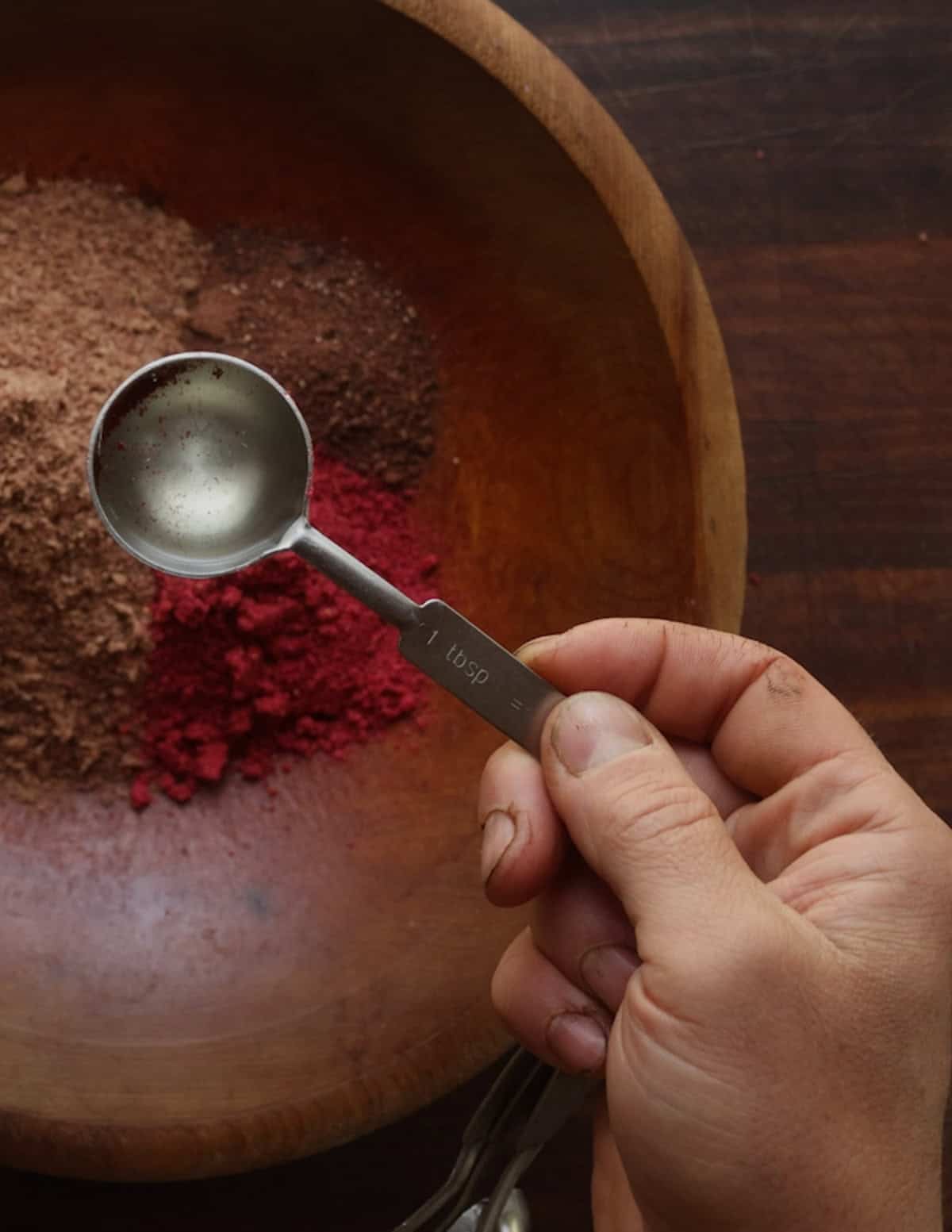 Adding melted beef tallow to a bowl of dried meat and fruit powders to make pemmican.
