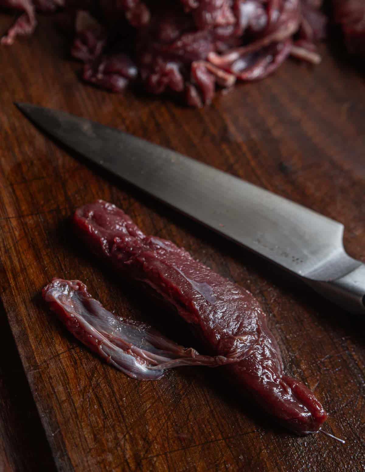 A close up image of cleaning venison meat and removing the silver skin from it before making pemmican.