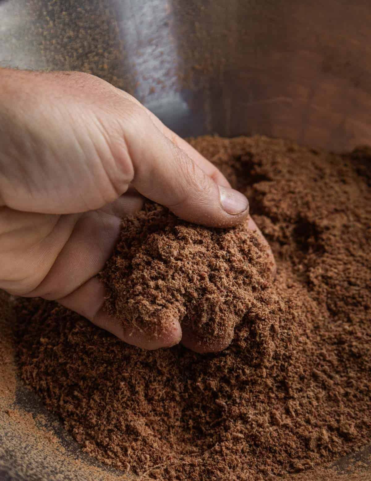 A hand holding smoked, dried and ground venison meat that's very fine, like a powder.