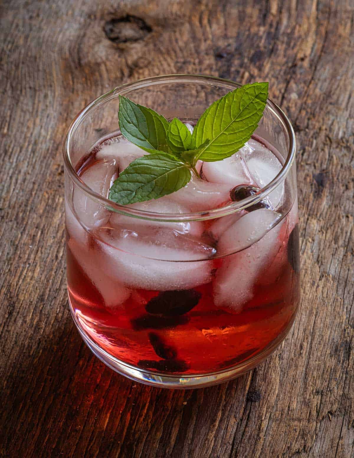 A glass of fruit kompot, a drink made from sugar or maple syrup, water and fresh haskap berries.