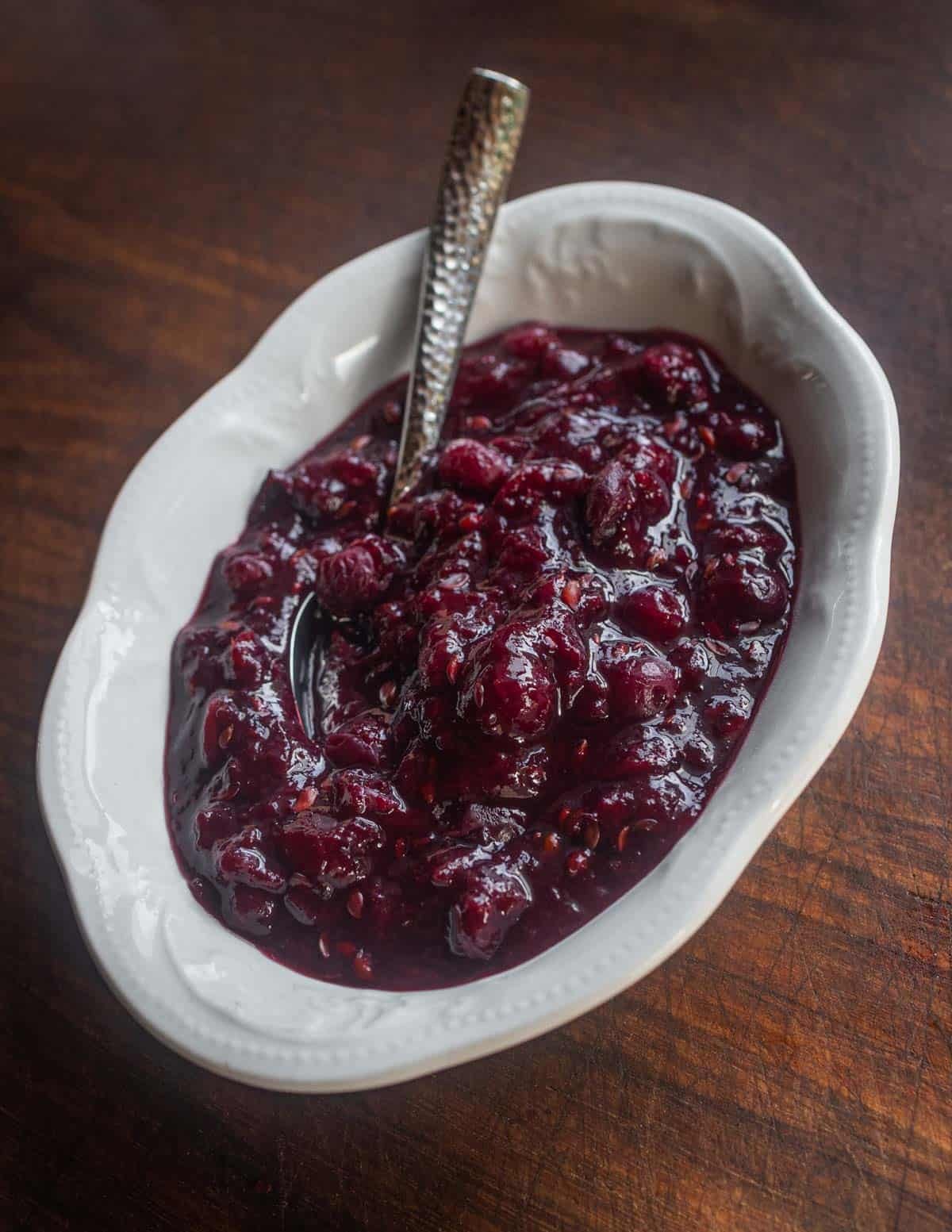 A bowl of chunky juneberry sauce or compote in a white China dish.