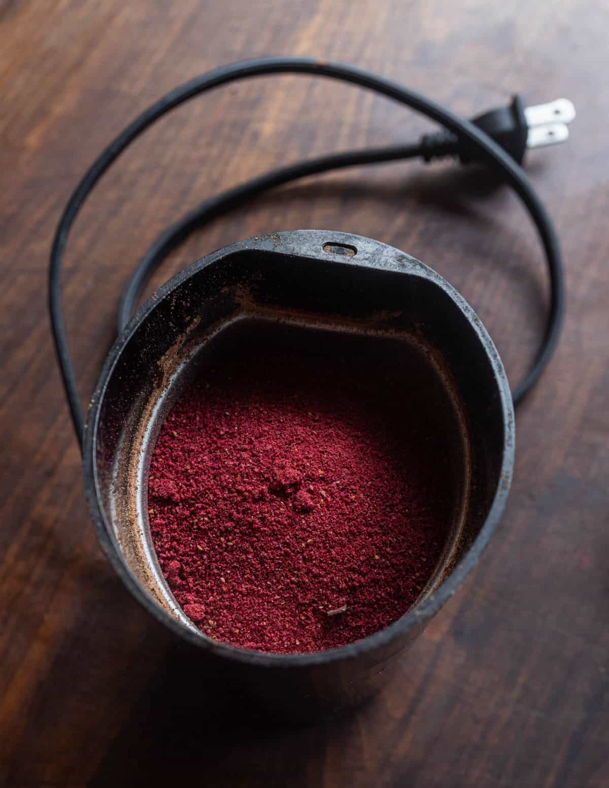 Grinding dried cranberries to a powder in a spice grinder.