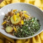 African style sweet potato leaf stew with wild rice and sweet potatoes garnished with herbs and nodding onion.