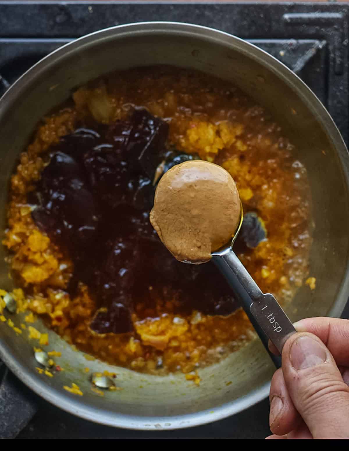 Adding a tablespoon of peanut butter to a pan of aromatics and meat stock.