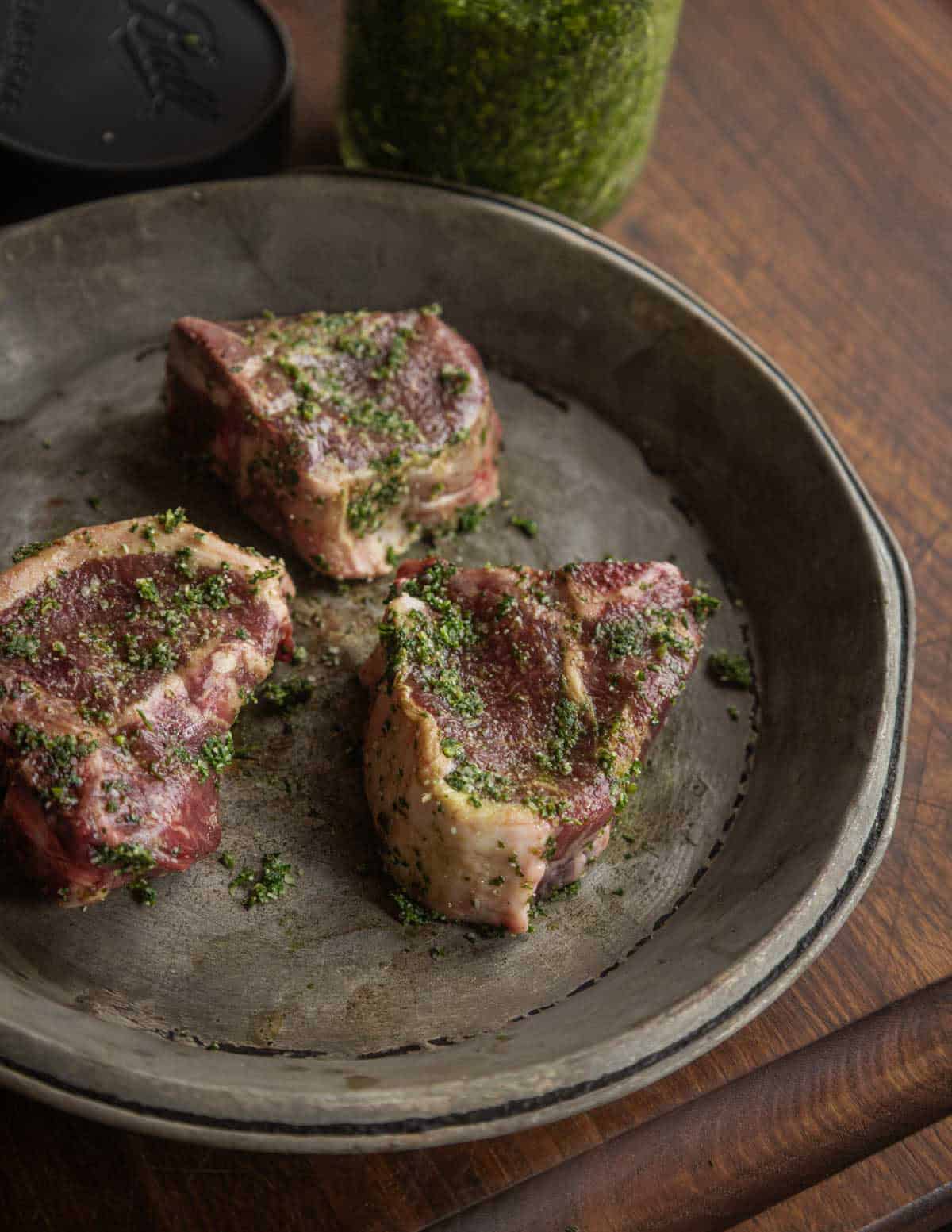 Lamb chops on an aluminum pie plate rubbed with garden herb salt.