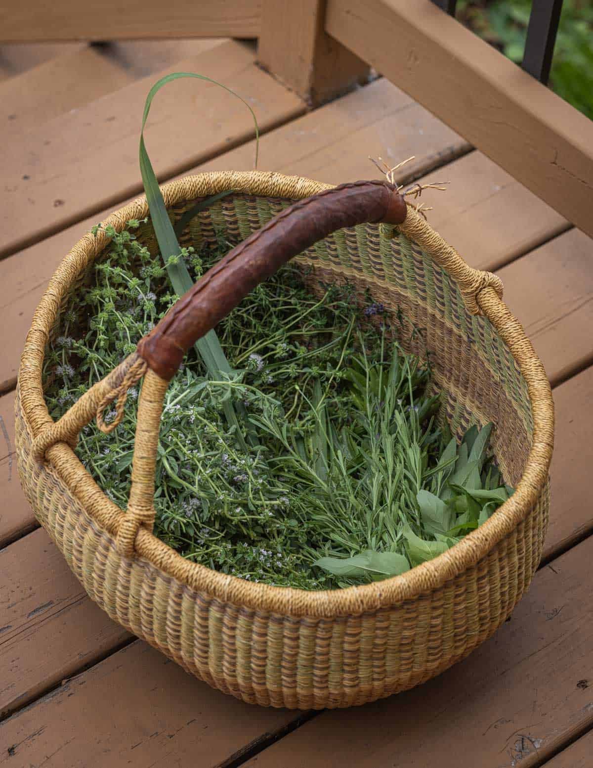 A large woven African basket filled with summer savory, lovage, thyme, lemon thyme, yarrow leaves, lemon grass, lemon verbena and marjoram.