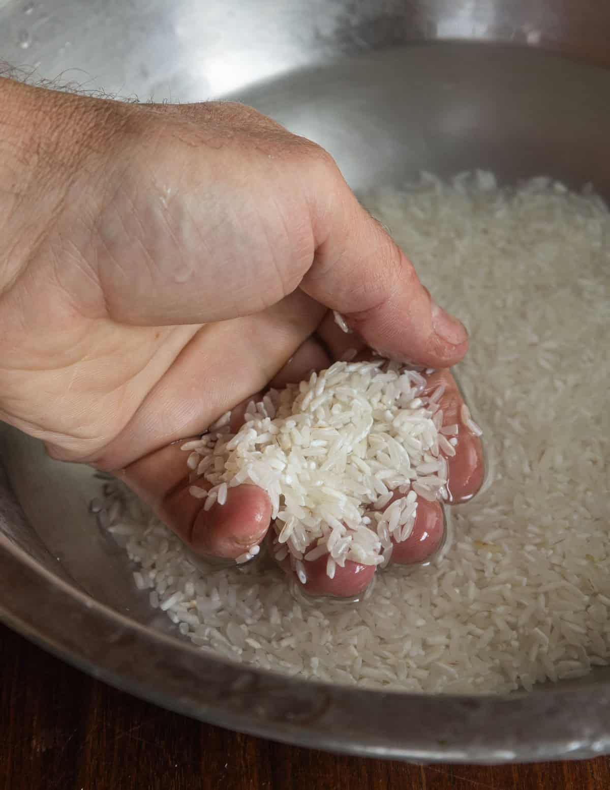 Rinsing rice with water to remove starch.