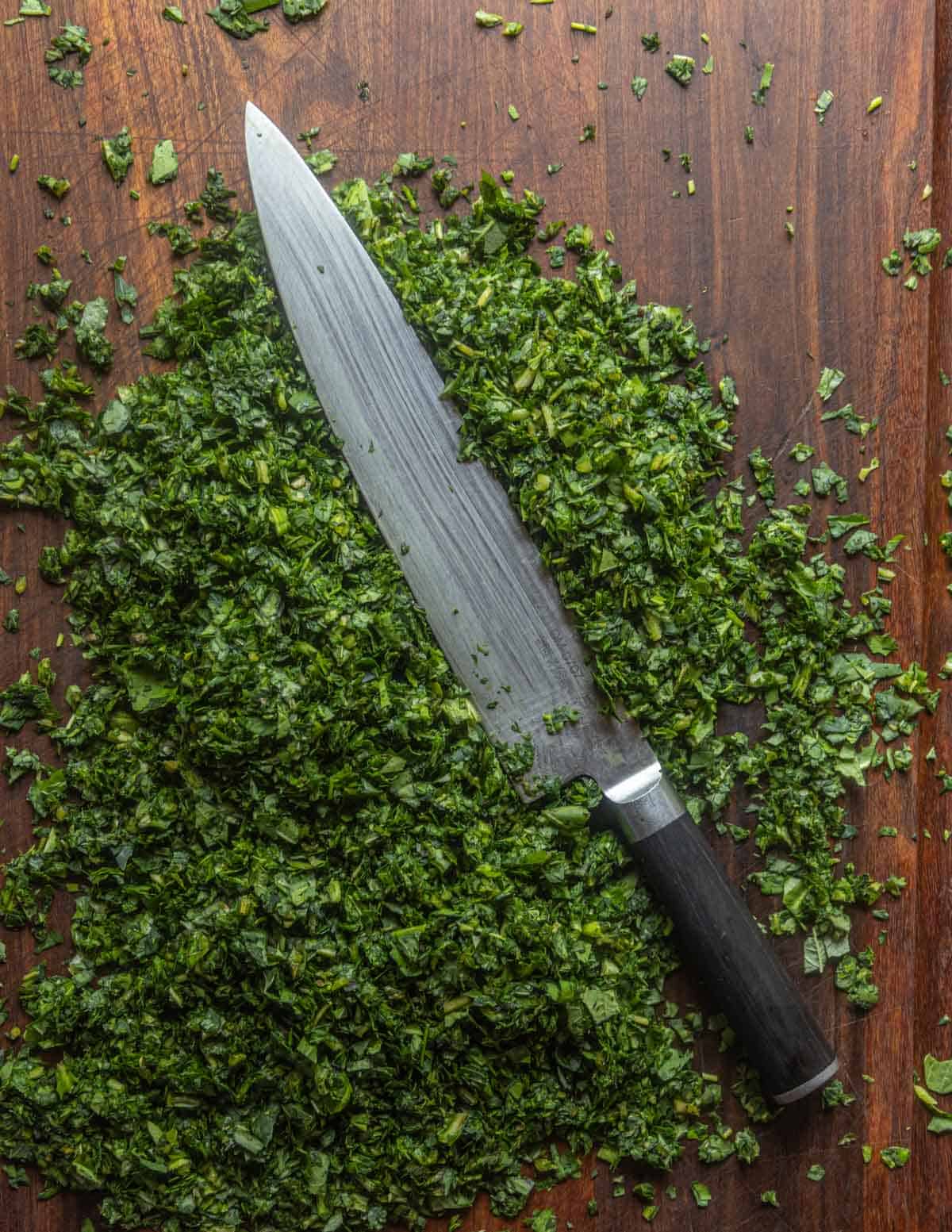 Finely chopping a large amount of spinach on a cutting board with a ten inch shun chef knife.