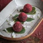 Small balls of pemmican or wasna rolled in cranberry powder and served on an anise hyssop leaf.