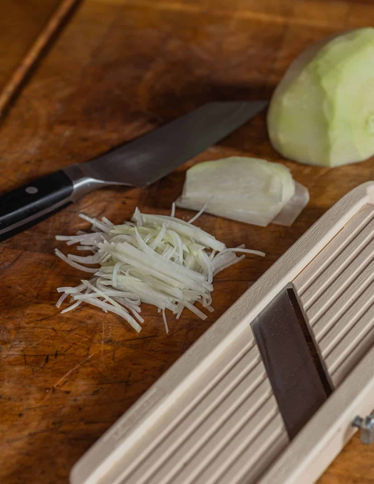 Cutting kohlrabi on a mandoline into slices and a thin julienne.