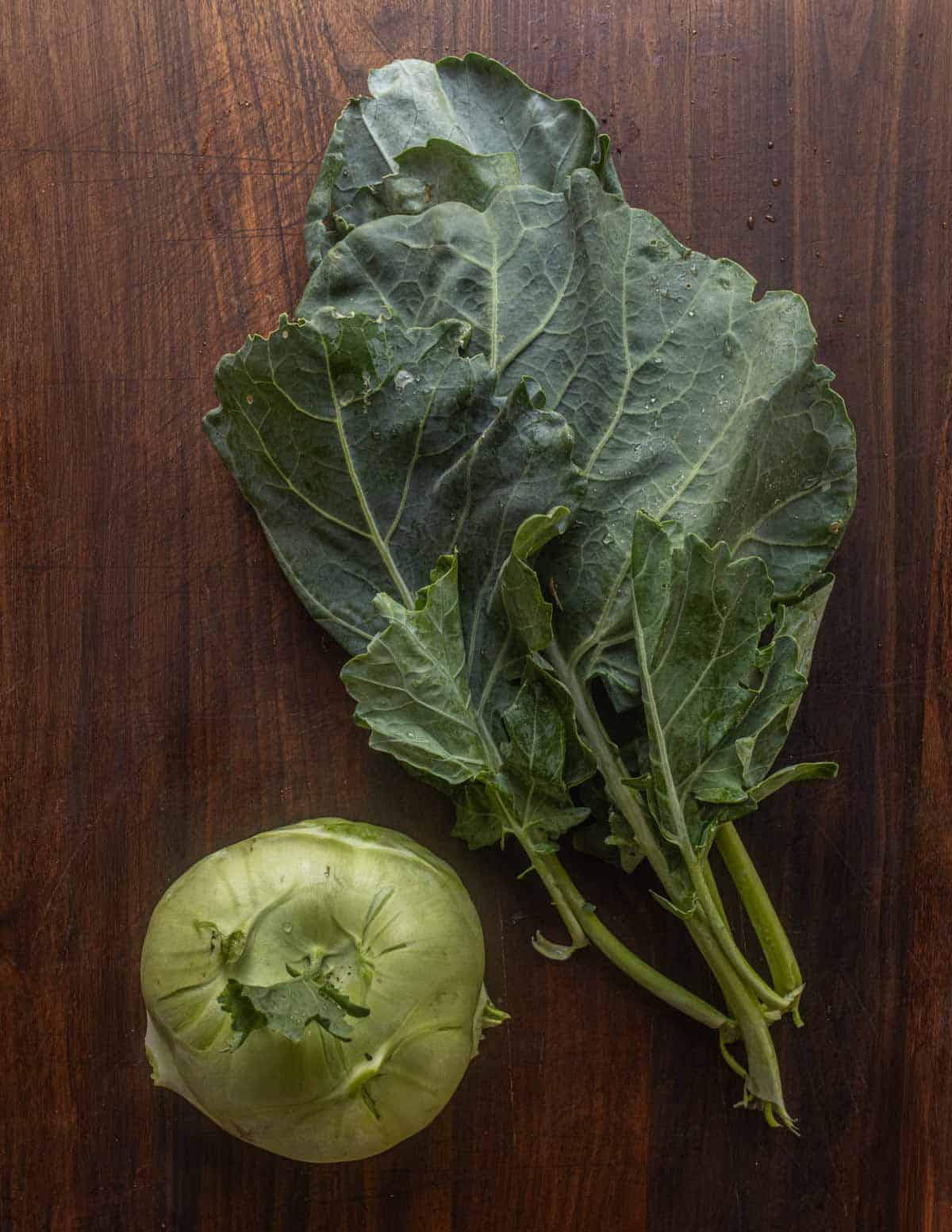 A top-down image showing kohlrabi greens being removed from the bulb.
