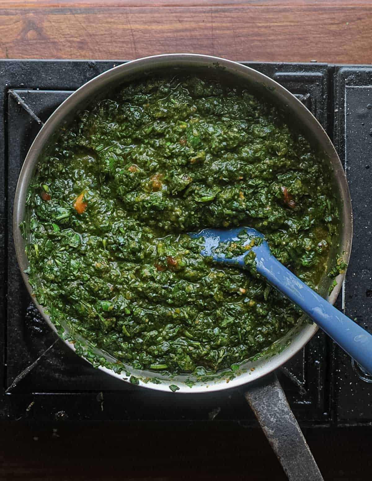 A top down image of sweet potato greens stew being cooked and ready to serve.