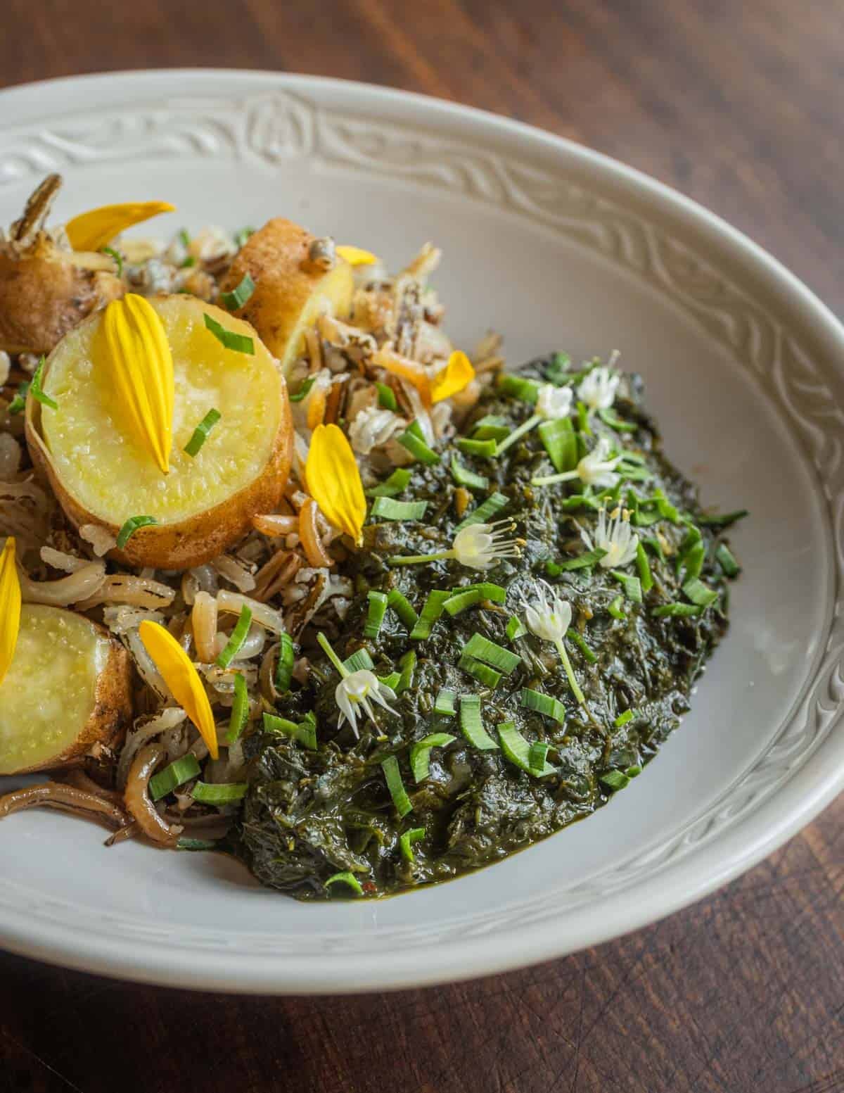 A bowl of wild rice and sliced white sweet potatoes served with an African sweet potato leaf stew from Guinea.