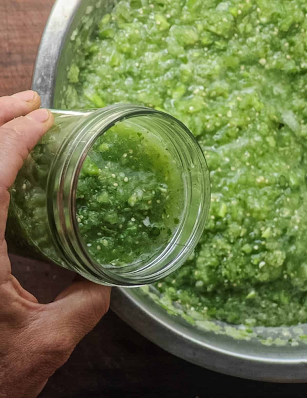 Portioning tomatillo and garlic scape salsa into a mason jar.