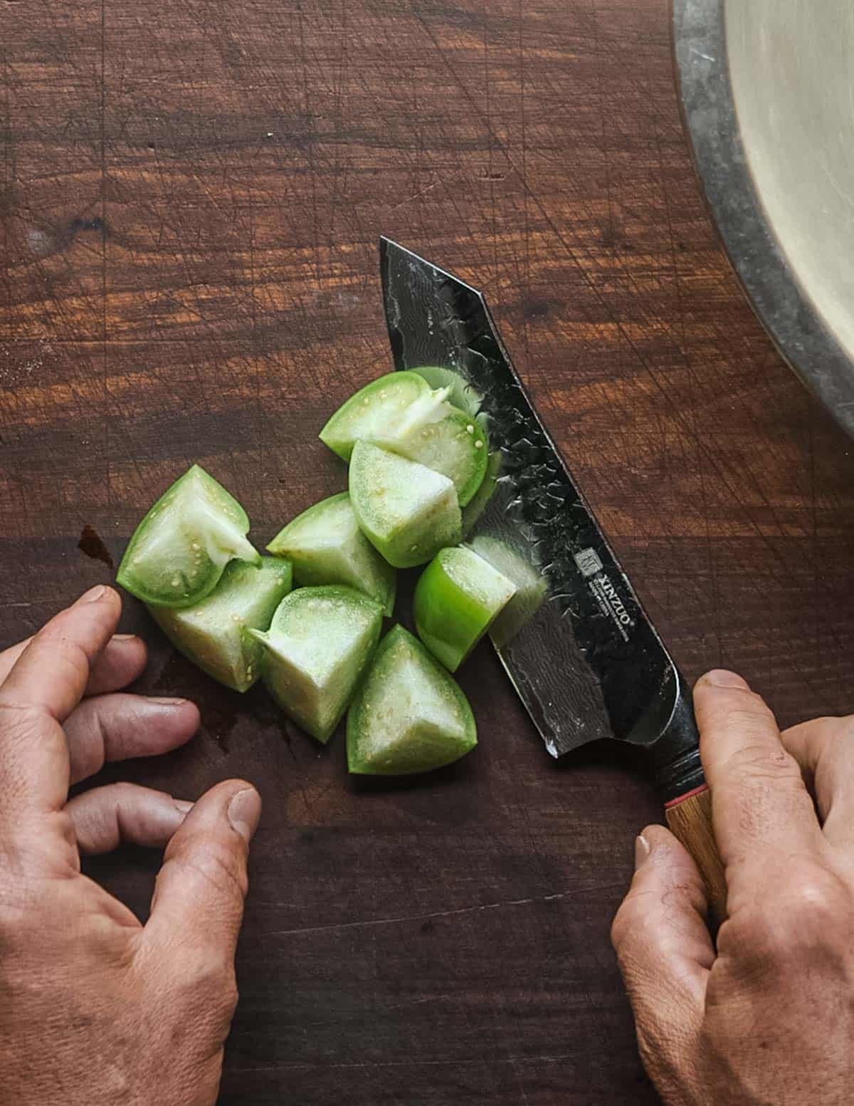 Cutting tomatillos into pieces for salsa.