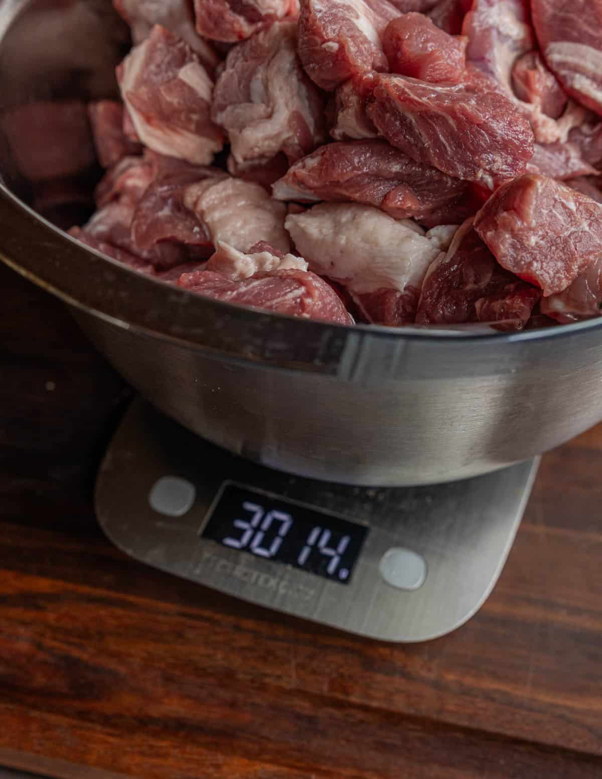 A bowl of diced pork shoulder on a scale to ensure proper seasoning.
